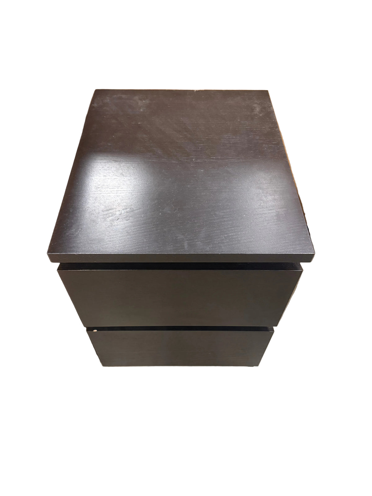 A dark brown wooden two-drawer nightstand or storage cabinet, photographed from a top-down angle in what appears to be a warehouse or showroom setting.