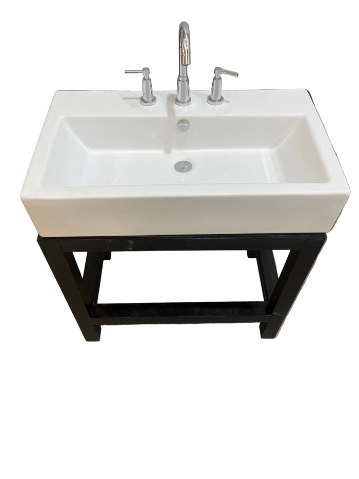 Rectangular white ceramic bathroom sink mounted on a black wooden base