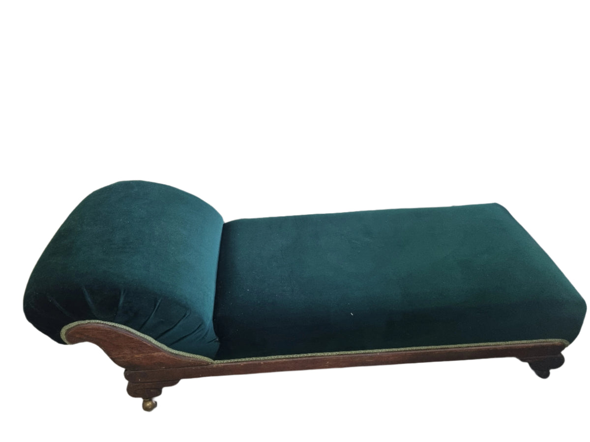 A vintage- style chaise lounge with green velvet