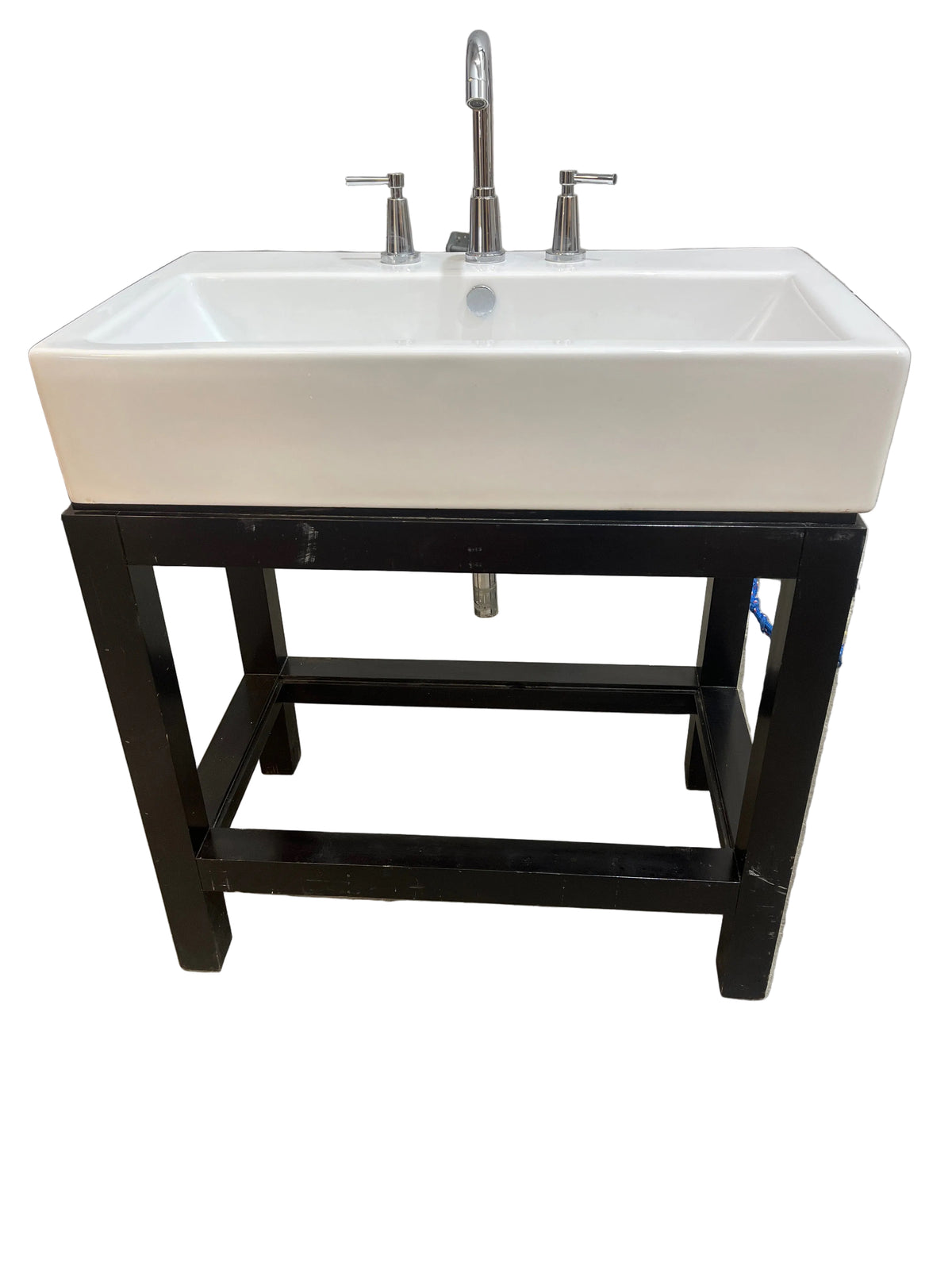 Rectangular white ceramic bathroom sink mounted on a black wooden base