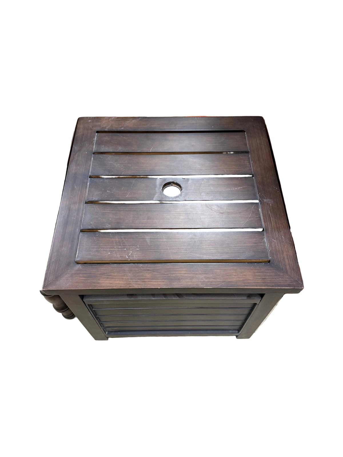 A dark brown wooden utility closet organizer or cabinet with a slatted front door and a circular hole in the center, shown next to other storage items on a concrete floor.
