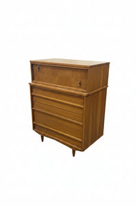 A mid-century modern wooden chest of drawers with a top cabinet and four drawers, shown in a furniture showroom.