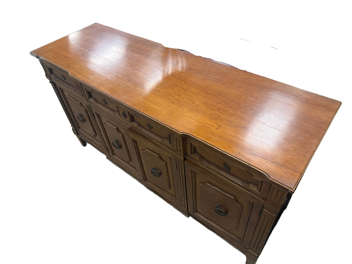 A medium brown wooden sideboard or credenza with multiple drawers and cabinet doors, shown in a furniture store setting.