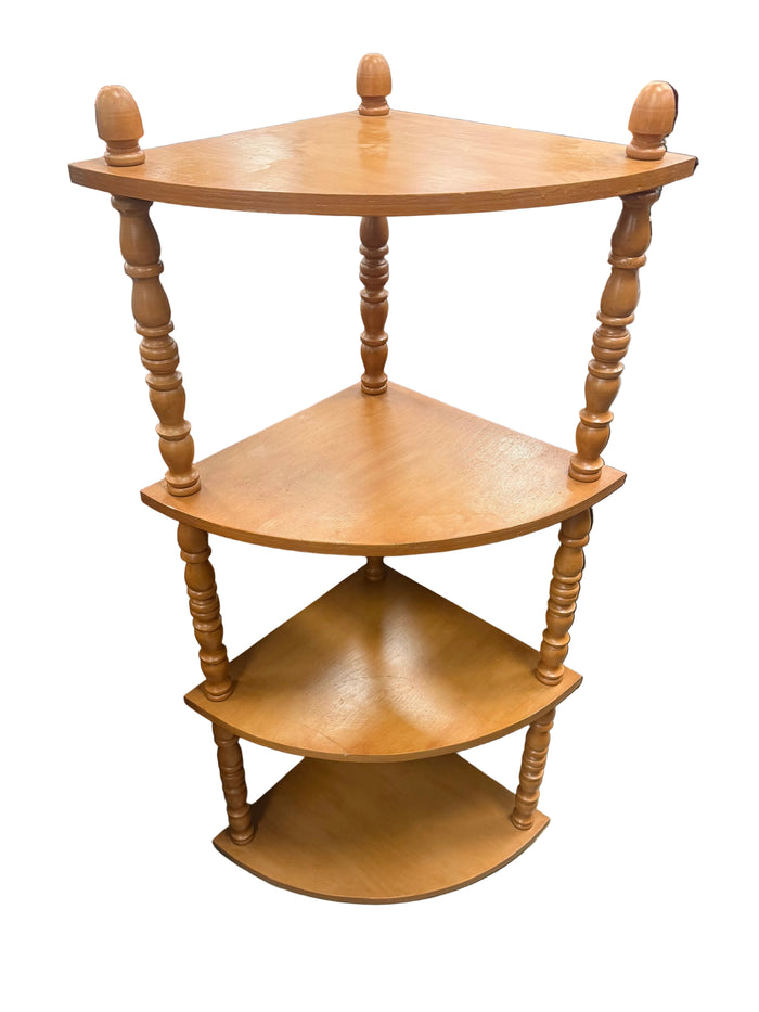 A three-tier corner wooden shelf with turned spindle legs, shown in a furniture store setting.