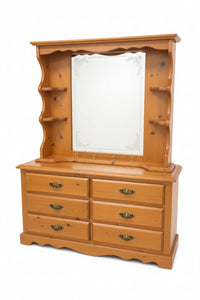 A warm honey-toned wooden dresser with an attached mirror and open shelving, photographed in a furniture store showroom.