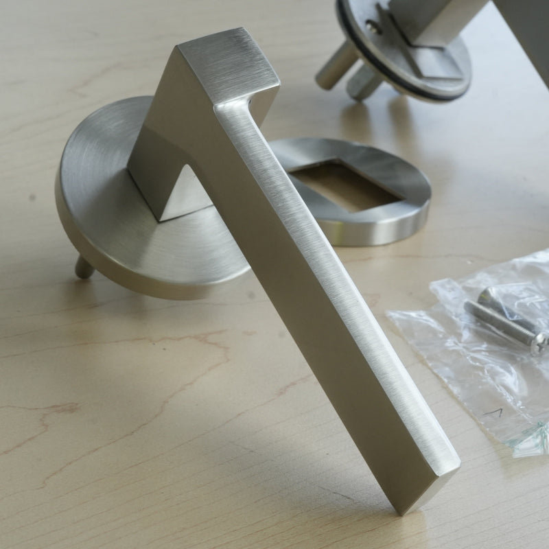 Metallic door handle on a wooden surface with packaging in the background