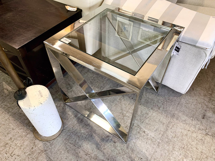 Modern glass side table with metallic base in a room setting