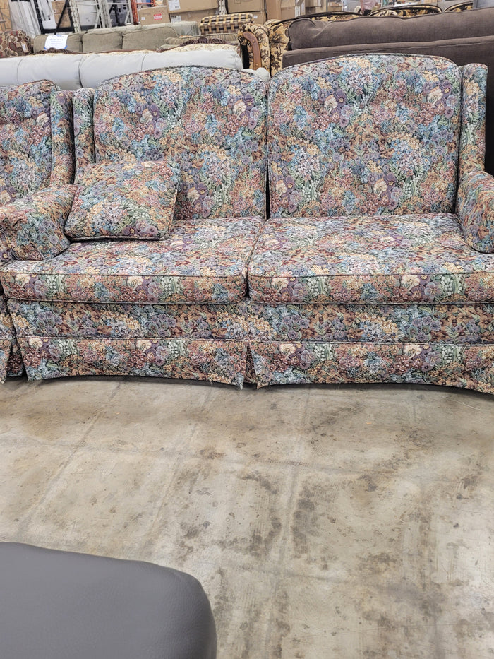 Vintage-Style Upholstered Loveseat With Multi-colored Floral Pattern.