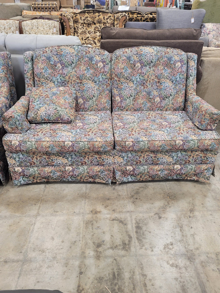 Vintage-Style Upholstered Loveseat With Multi-colored Floral Pattern.